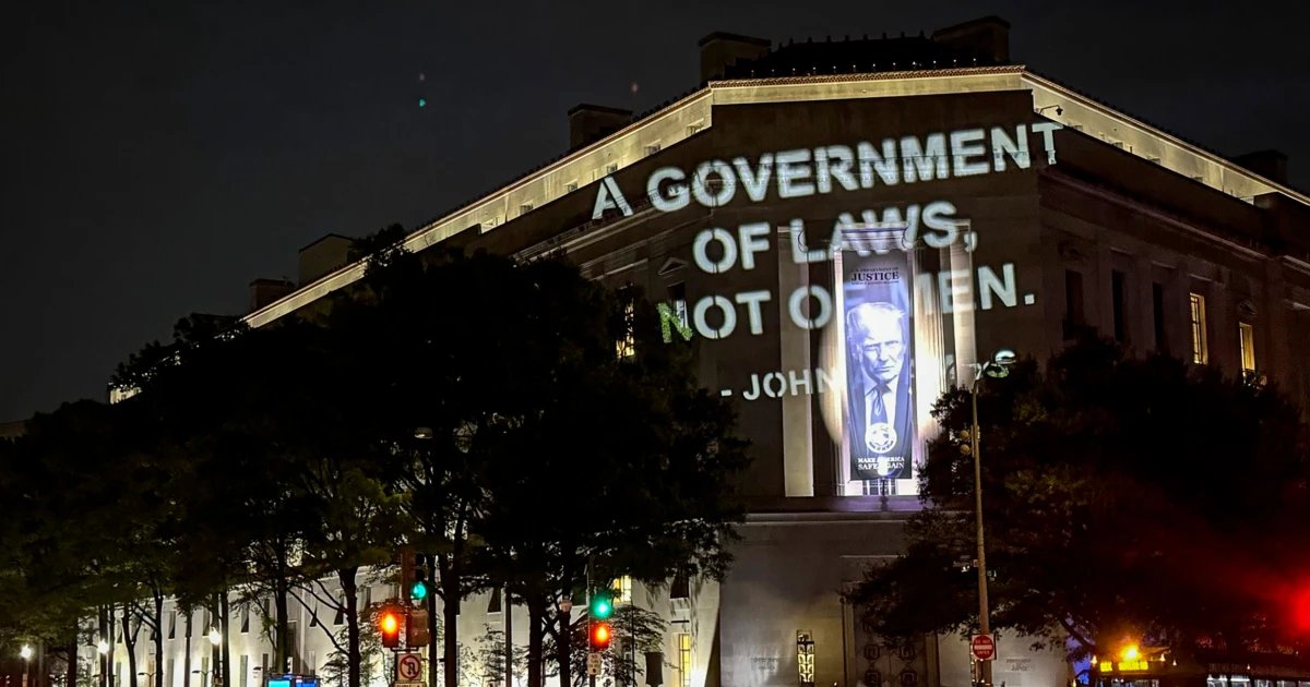 John Adams quote projected on DOJ building in protest of $1.8B fund